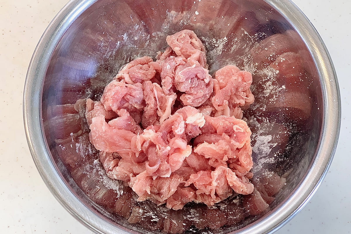 豚こま肉をボウルに入れ、塩、こしょう、薄力粉を揉み込んだところ