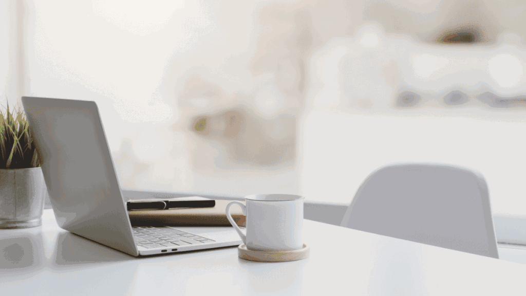 ノートパソコンとコーヒーのあるデスクの写真