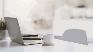 ノートパソコンとコーヒーのあるデスクの写真