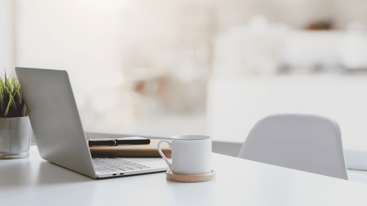 ノートパソコンとコーヒーのあるデスクの写真