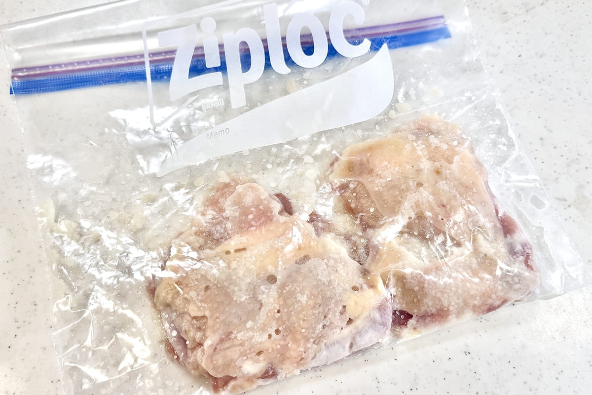 鶏肉を食品用ポリ袋に入れ、塩糀に漬け込んでいる様子